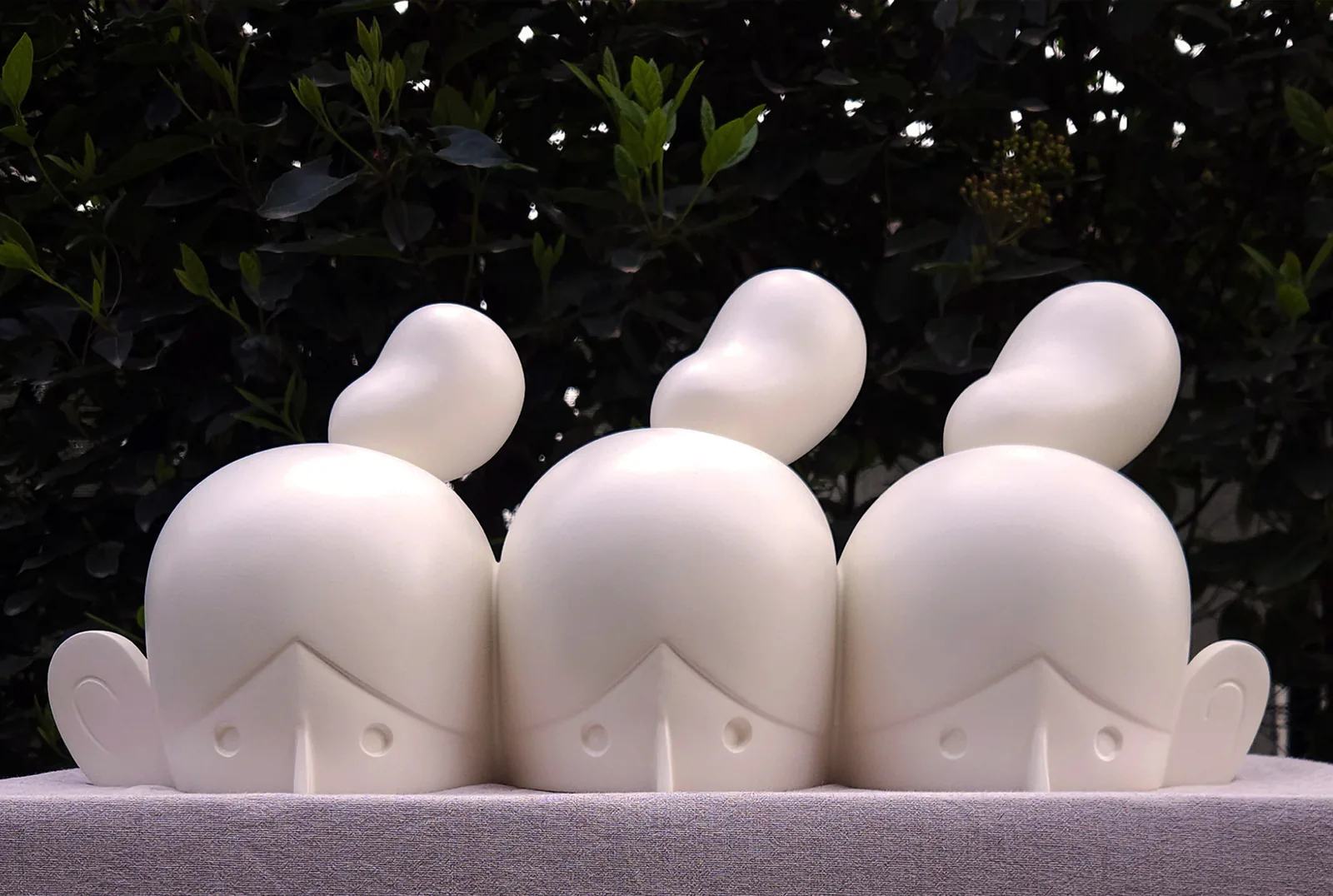 Drowning, Splitting, Multiplying — three cream cast-polyester figures by Sibel Açıkalın Akgün, photographed outdoors