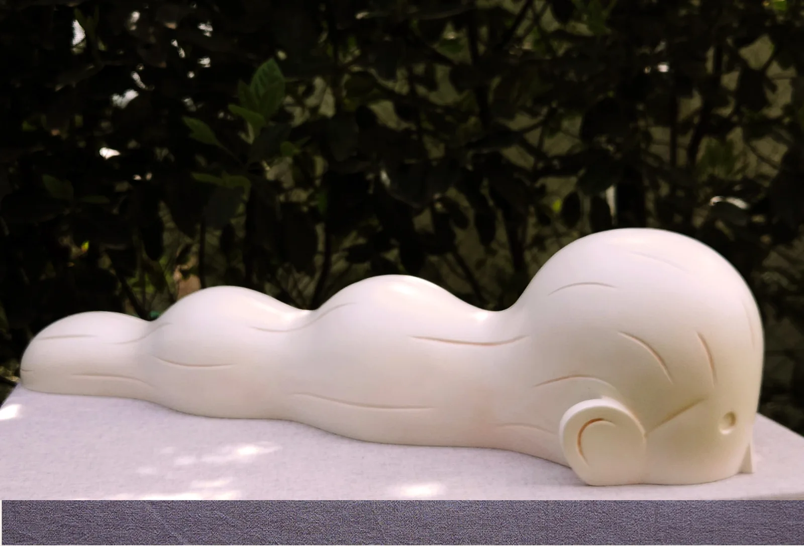 Flow — an elongated reclining cream form with soft undulating waves, cast polyester sculpture