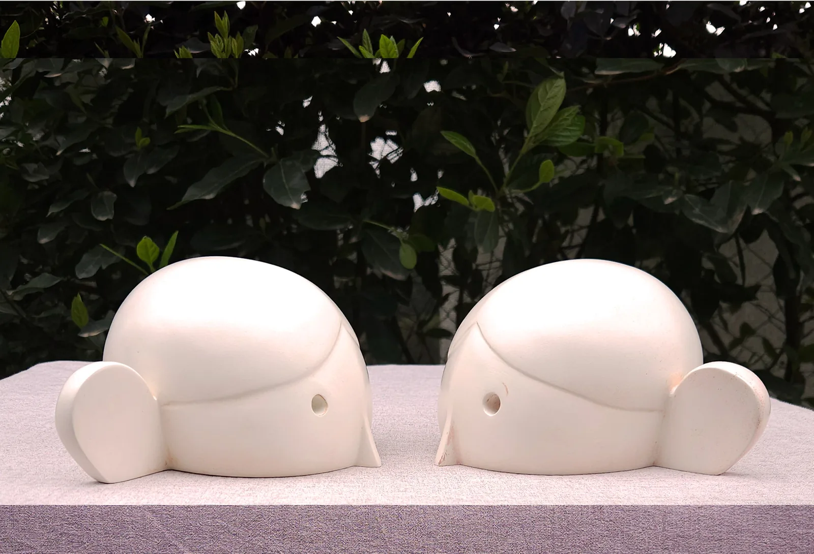 Leave Me Alone — two rounded cream heads with small ears facing one another, cast polyester sculpture